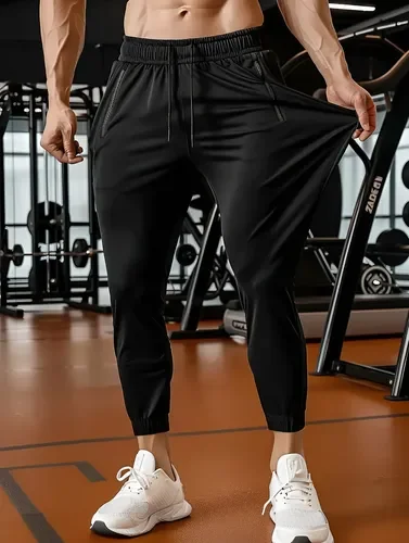 Calça jogger masculina preta UseBliss com punho no tornozelo, vestida com tênis branco