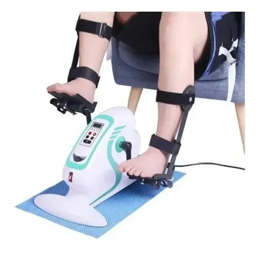 Mini bike motorizada branca e verde-água sobre um tapete azul, com os pés e as mãos de uma pessoa sentada presos por tiras e o fio de energia à mostra